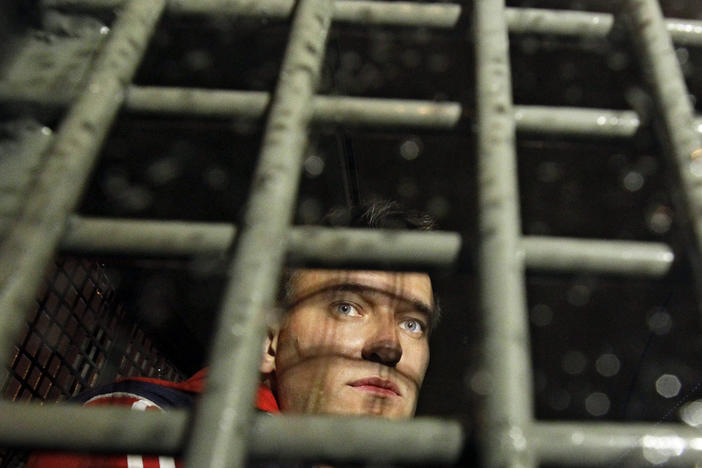 Alexei Navalny is seen in 2012 behind the bars in a police van after he was detained during protests in Moscow a day after Vladimir Putin's inauguration.