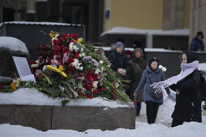 People lay flowers paying the last respect to Alexei Navalny at the monument, a large boulder from the Solovetsky islands, where the first camp of the Gulag political prison system was established, near the historical the Federal Security Service (FSB, Soviet KGB successor) building in the background, in Moscow, Russia, on Saturday morning, Feb. 17, 2024.