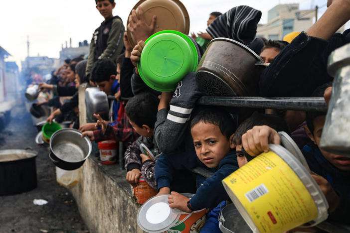 Palestinian children wait to collect food at a donation point in a refugee camp in Rafah in the southern Gaza Strip on December 23, 2023.