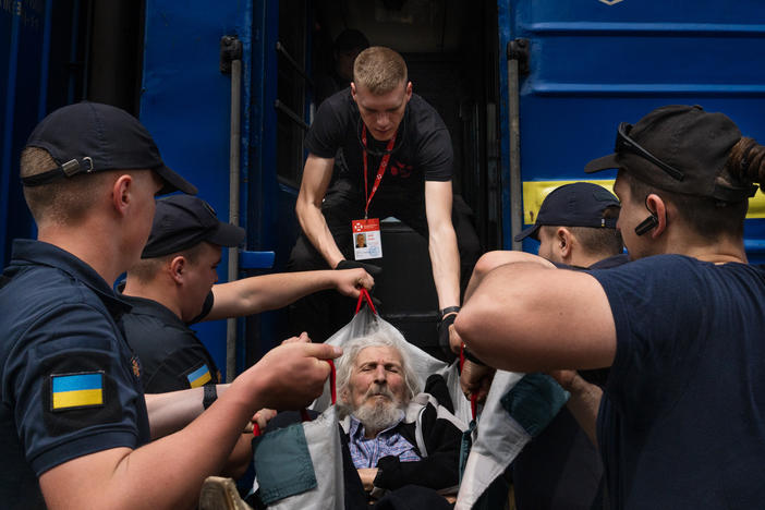 Eduard Skoryk (center) helps lift Viktor Nesterov onto an evacuation train leaving Toretsk, in eastern Ukraine, in May.