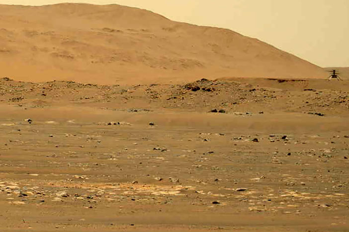 In this April 30, 2021, file image taken by the Mars Perseverance rover and made available by NASA, the Mars Ingenuity helicopter, right, flies over the surface of the planet.