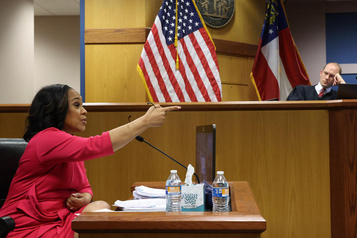 Fulton County District Attorney Fani Willis speaks from a witness stand in front of Fulton Superior Judge Scott McAfee during a Feb. 15 hearing about whether Willis' office should be disqualified from the Georgia election interference case.