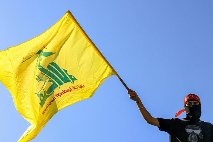A masked demonstrator waves a flag of Hezbollah during a demonstration supporting the Palestinians in Beirut on Oct. 20, 2023.