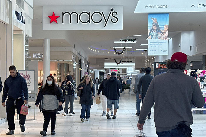 Shoppers walk by a sign for the Macy's department store at a mall in Long Island, N.Y.