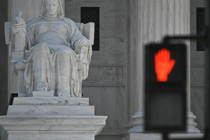 The Supreme Court, seen behind the stop light, is hearing arguments in a case testing the legality of a federal regulation banning devices that modify semiautomatic weapons to speed the firing mechanism.