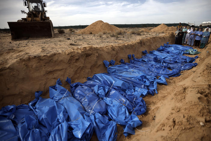 Palestinians pray over bodies of people killed in an Israeli bombardment, brought from the Shifa hospital, before burying them in a mass grave in the town of Khan Younis, southern Gaza Strip, Nov. 22.
