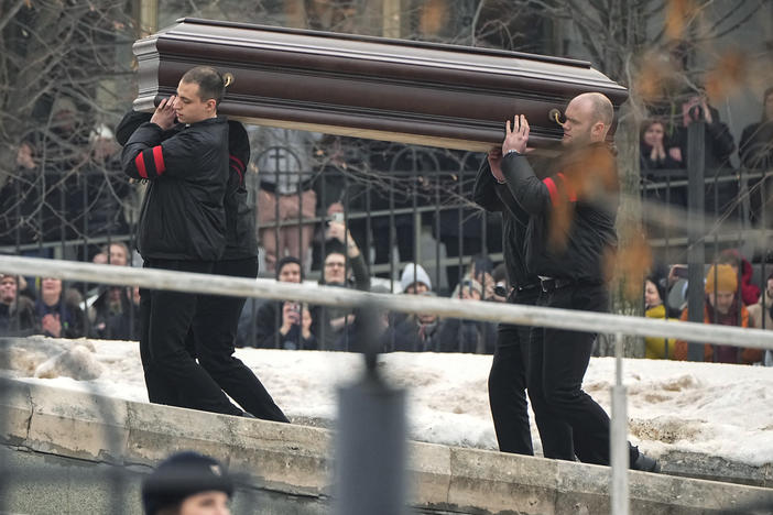 People watch as workers carry the coffin of Russian opposition leader Alexei Navalny to the Church of the Icon of the Mother of God "Relieve My Sorrows" in Moscow, Friday.