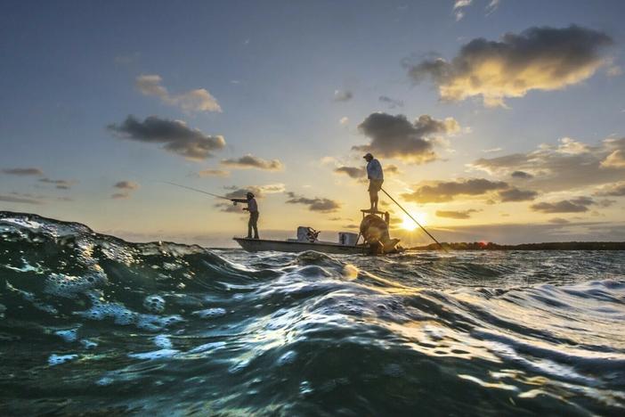 Florida Keys Fishing Captain Tim Klein directs a fly fishing client to fish off of Islamorada as the sun rises over Florida Bay.