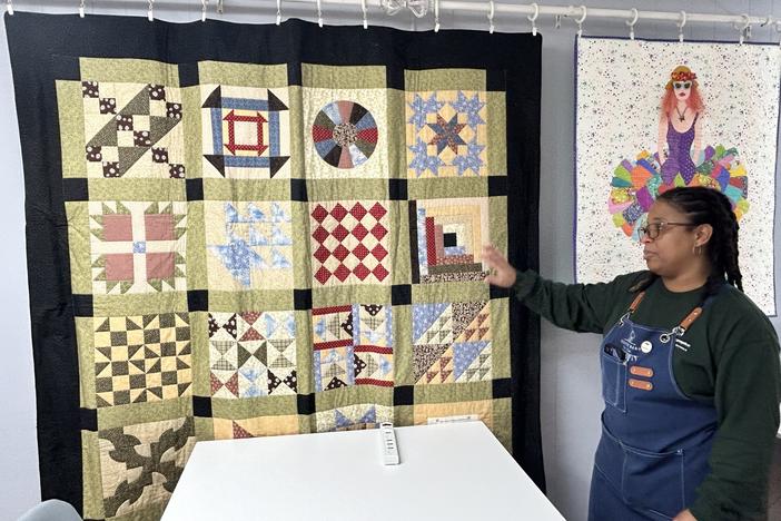 Sandra Daniel stands before an Underground Railroad Quilt Code quilt hanging in her store, Country Barn Quilt Co.