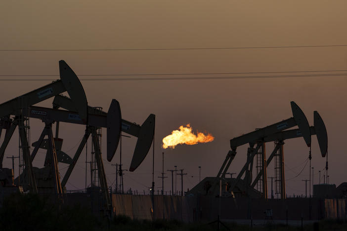 A flare burns off methane and other hydrocarbons as oil pumpjacks operate in the Permian Basin in Midland, Texas. Burning fossil fuels like coal, oil and natural gas is the main driver of global warming.