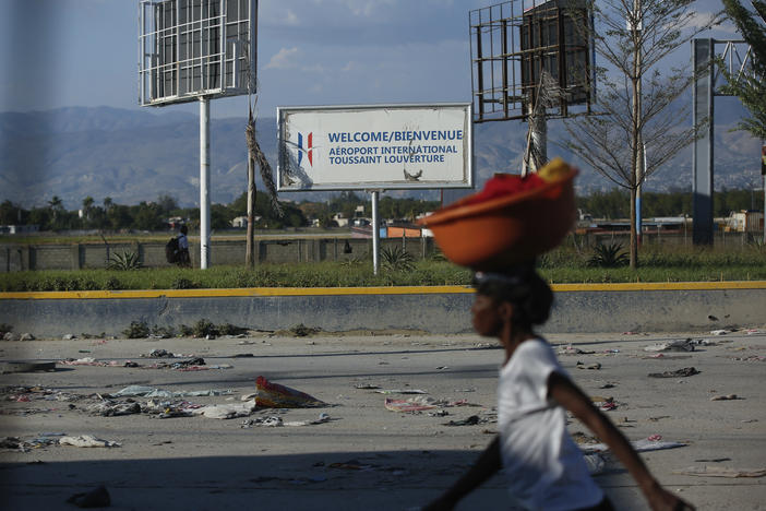 A pedestrian walks past the international airport in Port-au-Prince, Haiti, Monday. Gang members exchanged gunfire with police and soldiers around the airport in the latest of a series of attacks on government sites.
