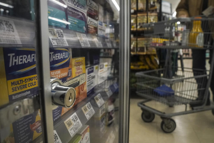 Medications are locked in a glass cabinet at a supermarket.