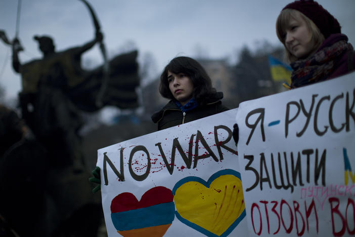 Two Ukrainian citizens hold up posters against Russia's military intervention.