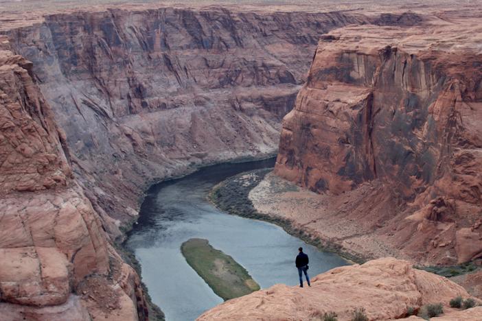 A man looks out over the Colorado River near Page, Arizona on Nov. 2, 2022. The seven states that manage the river are divided about how to account for the impacts of climate change in new plans about sharing its water.