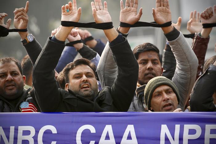 Indians raise their tied hands and shout slogans during a protest against the Citizenship Amendment Act in New Delhi, India, Dec. 27, 2019. Prime Minister Narendra Modi's government on Monday announced rules to implement a 2019 citizenship law that critics say is discriminatory against Muslims, weeks before the Hindu nationalist leader will seek a third term in office.