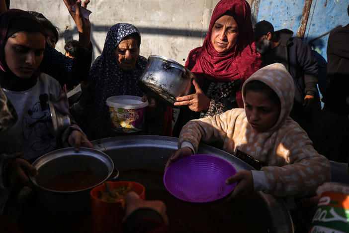 Displaced Palestinians gather to receive food donated by a charity before an iftar meal, the breaking of fast, on the second day of the Muslim holy fasting month of Ramadan, in Deir al-Balah, central Gaza Strip, Tuesday, amid ongoing battles between Israel and the militant group Hamas.