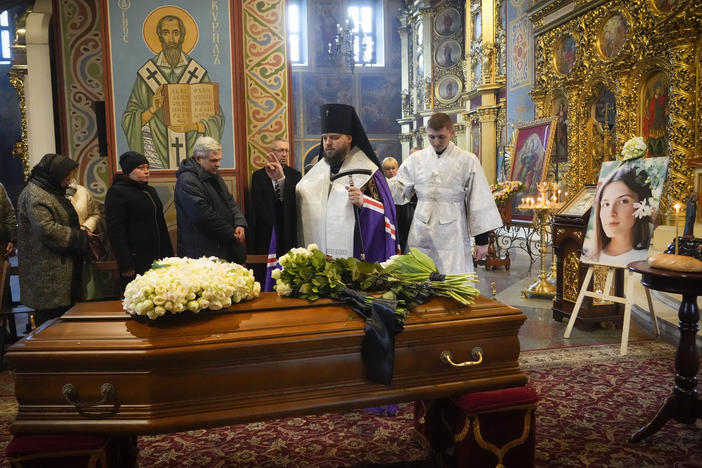 A priest prays over the coffin of Oleksandra "Sasha" Kuvshynova, a Ukrainian journalist killed while working for Fox News in March 2022. Her parents have sued Fox News alleging wrongful death, fraud and defamation.