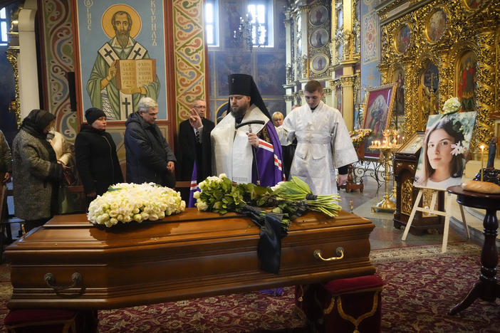 A priest prays over the coffin of Oleksandra "Sasha" Kuvshynova, a Ukrainian journalist killed while working for Fox News in March 2022. Her parents have sued Fox News alleging wrongful death, fraud and defamation.