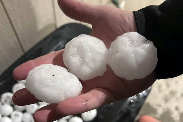 In this image provided by Jeremy Crabtree, large chunks of hail are shown Wednesday night, in Shawnee, Kan. Volatile weather honed in on parts of Kansas and Missouri, with some storms dumping massive chunks of hail.