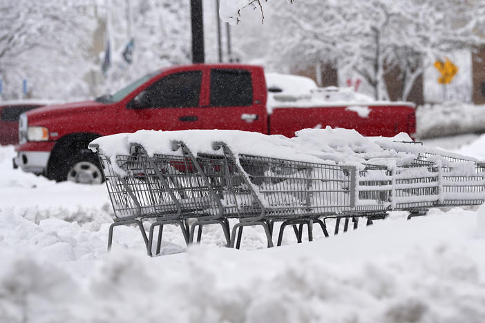 Shopping carts topped with heavy snow sit marooned in the lot of a grocery store as a late winter storm dropped up to a foot of snow Thursday, March 14, 2024, in Golden, Colo.