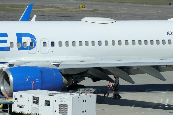 A Medford Jet Center worker walks under a United Boeing 737-824 that landed at Rogue Valley International-Medford Airport from San Francisco with a missing panel on Friday in Medford, Ore.