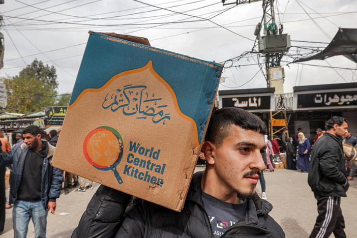A man carries a cardboard box of food aid provided by nonprofit organization World Central Kitchen in Rafah, in southern Gaza, on March 17, amid the conflict between Israel and the militant group Hamas.