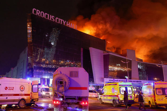 Vehicles of Russian emergency services are parked near the burning Crocus City Hall concert venue, following a reported shooting incident, outside Moscow on Friday.