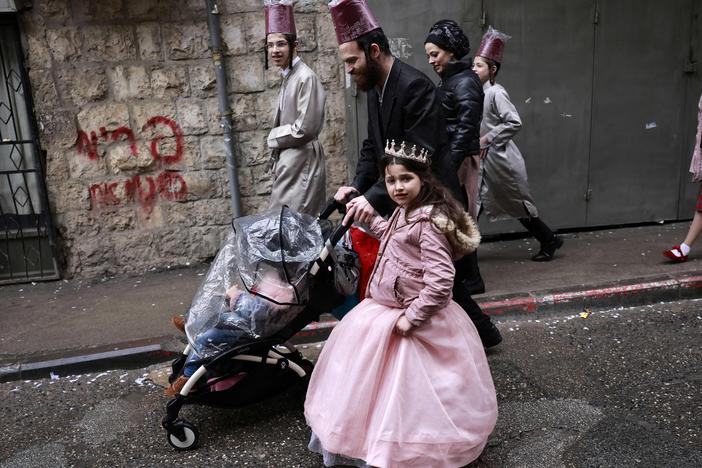 Jewish men and children in Purim costumes celebrate in the Mea Shearim ultra-Orthodox neighbourhood in Jerusalem, on March 18, 2022. The Purim holiday is celebrated with parades and costume parties to commemorate the deliverance of the Jewish people from a plot to exterminate them in the ancient Persian empire 2,500 years ago, as recorded in the Biblical Book of Esther.