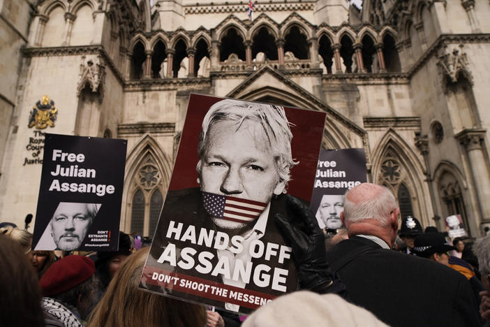 A demonstrator holds a placard, after Stella Assange, wife of WikiLeaks founder Julian Assange, released a statement outside the Royal Courts of Justice, in London, Tuesday.