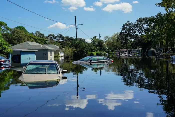 Clouds are reflected on a flooded street with submerged cars in the Orlovista neighborhood following Hurricane Ian on October 1, 2022 in Orlando, Florida.