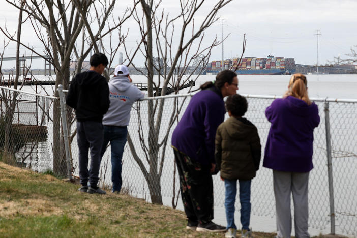 Residents look on after a cargo ship ran into and collapsed the Francis Scott Key Bridge on March 26, 2024 in Baltimore. Conspiracy theorists online quickly spread narratives to millions online that the accident was part of a nefarious scheme.