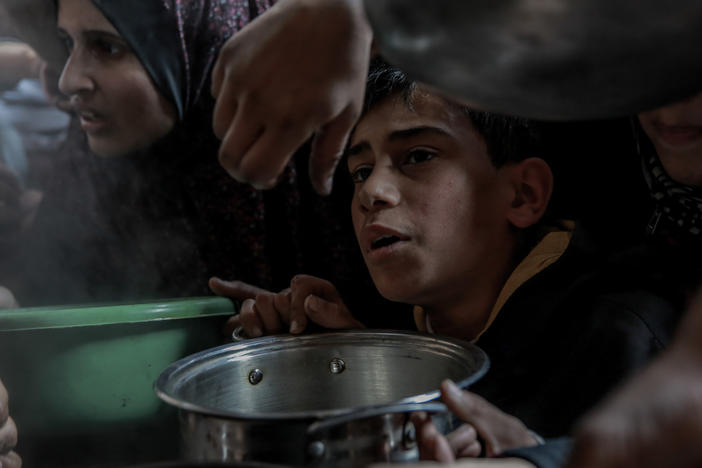 A Palestinian boy waits with his pot among a crowd in Beit Lahia, in northern Gaza, while trying to get a small amount of soup from one of the few soup kitchens, on Feb. 26.