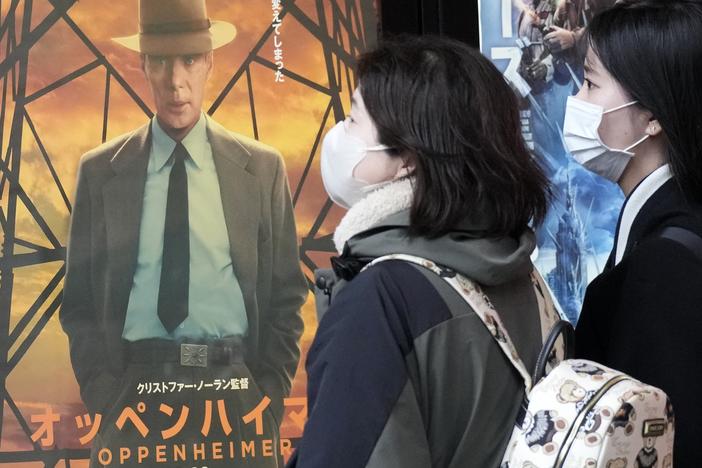 People walk by a poster to promote the movie <em>Oppenheimer</em> on Friday in Tokyo.