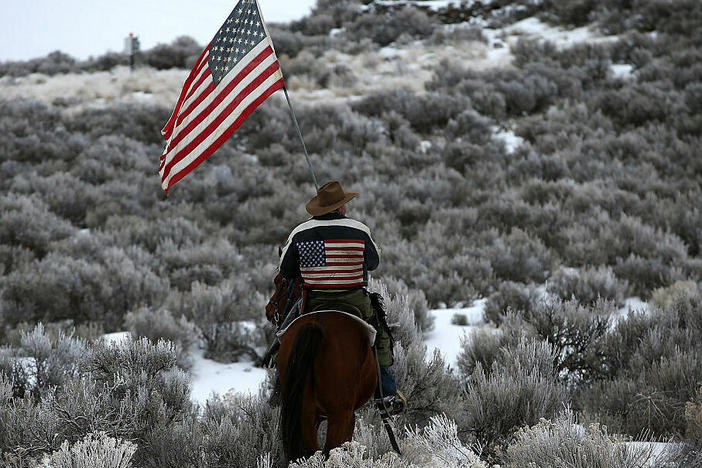 Dwayne Ehmer carries a U.S. flag as he rides his horse on the Malheur National Wildlife Refuge on Jan. 7, 2016, near Burns, Ore. An armed anti-government militia occupied the headquarters there to protest the jailing of two ranchers accused of arson.