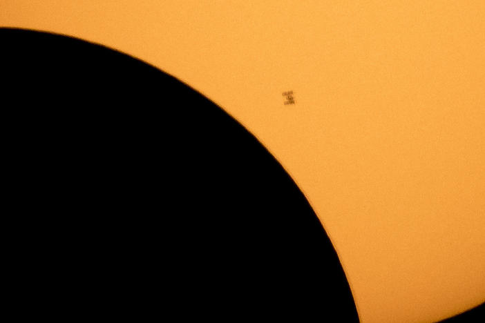 In this image made available by NASA, the International Space Station is silhouetted against the sun during a solar eclipse Monday, Aug. 21, 2017, as seen from Ross Lake, Northern Cascades National Park in Washington state.