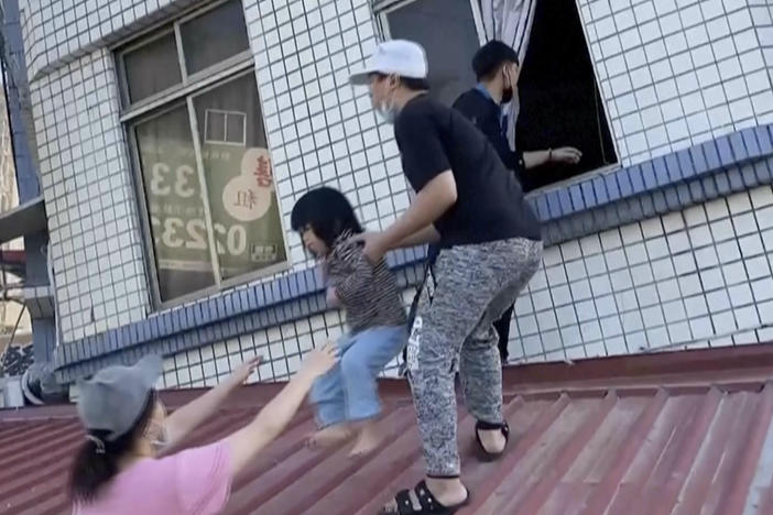 In this image taken from a video footage run by TVBS, residents rescue a child from a partially collapsed building in Hualien, eastern Taiwan on Wednesday.