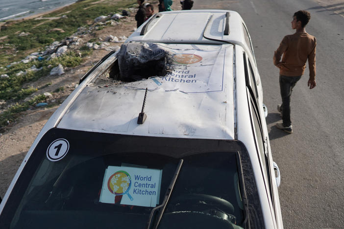 People gather around the wreckage of a car used by the U.S.-based aid group World Central Kitchen on Tuesday after it was hit by an airstrike the previous day in Deir al-Balah in the central Gaza Strip.