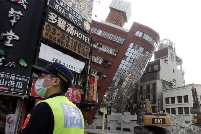 A police officer stands guard near a partially collapsed building a day after a powerful earthquake struck in Hualien City, eastern Taiwan, Thursday, April 4, 2024.
