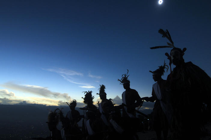 Dancers perform as a solar total eclipse occurs in Matantimali, Central Sulawesi on March 9, 2016.