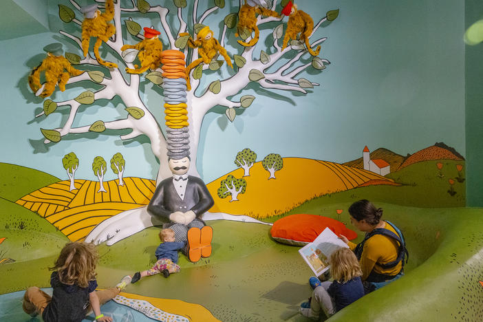 Lindsey Anderson sits down to read <em>Caps for Sale</em> by Esphyr Slobodkina to her children Orion, 6, Arthur, 4, and Thora Hoke, 1, inside the exhibit inspired by the book inside The Rabbit hOle, an immersive museum dedicated to children's literature, in North Kansas City, Mo.