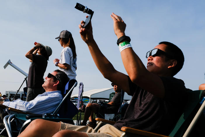 Amos Yew, right, uses a lens on an iPhone to record video in the first stages of the total solar eclipse Monday August 21, 2017 in Madras, Oregon.