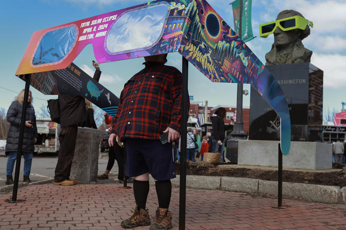 Visitors look through a pair of oversized eclipse glasses set up in the town square on Sunday in Houlton, Maine.