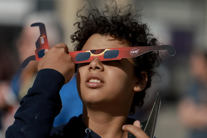 Junior Espejo looks through eclipse glasses being handed out by NASA in Houlton, Maine. Used correctly, eclipse glasses prevent eye damage.