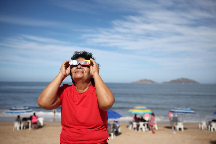 A woman puts on special glasses to see the eclipse on Monday in Mazatlán, Mexico. Many people have flocked to the seaside area to catch a glimpse of the total solar eclipse.