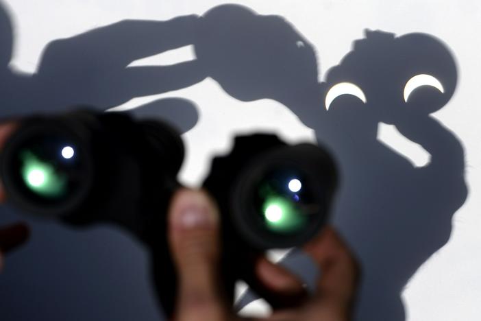 A person uses a pair of binoculars to watch the moon pass infront of the Earth's star marking a total eclipse in Vigo, northwestern Spain on March 20, 2015.