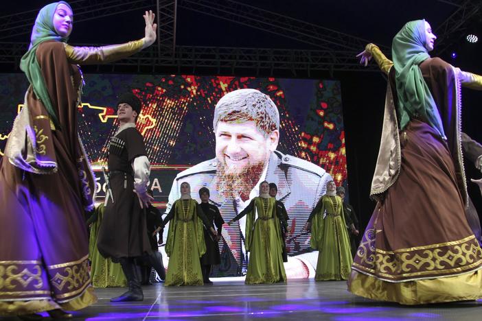 Dancers wearing Chechen national costumes perform to celebrate the reelection of Chechnya's regional leader Ramzan Kadyrov (pictured in the background) in Grozny, Russia in September 2021.