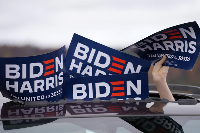 A person holds signs from the sunroof of a vehicle during a campaign event for Joe Biden.