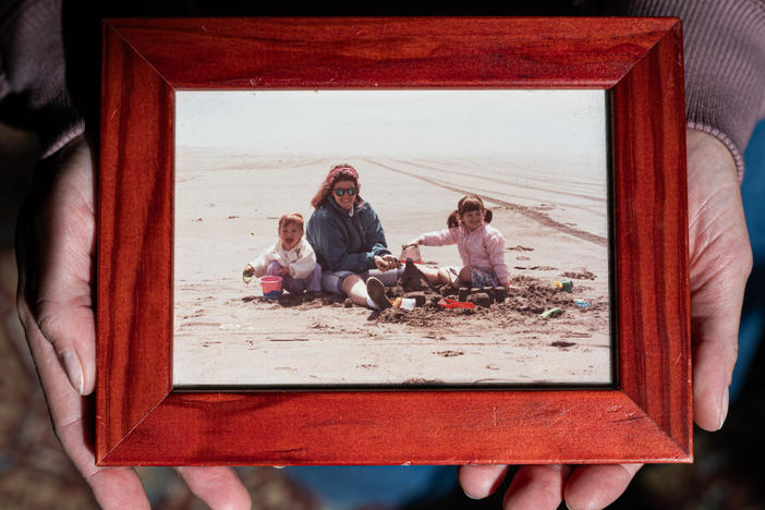 Simone Elliot holds a childhood photo of she and her sister with their mother.