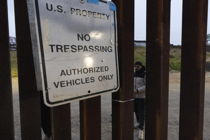 Migrants wait between border walls separating Tijuana, Mexico, and San Diego, to apply for asylum with U.S. authorities on Friday.