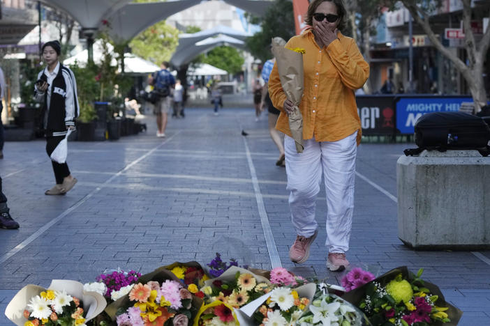 A woman brings flowers to an impromptu memorial at Bondi Junction in Sydney, Sunday, April 14, 2024, after several people were stabbed to death at a shopping center Saturday.